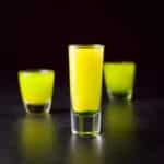 Vertical view of the tall glass filled with the layered shot with the other two glasses in the back - square