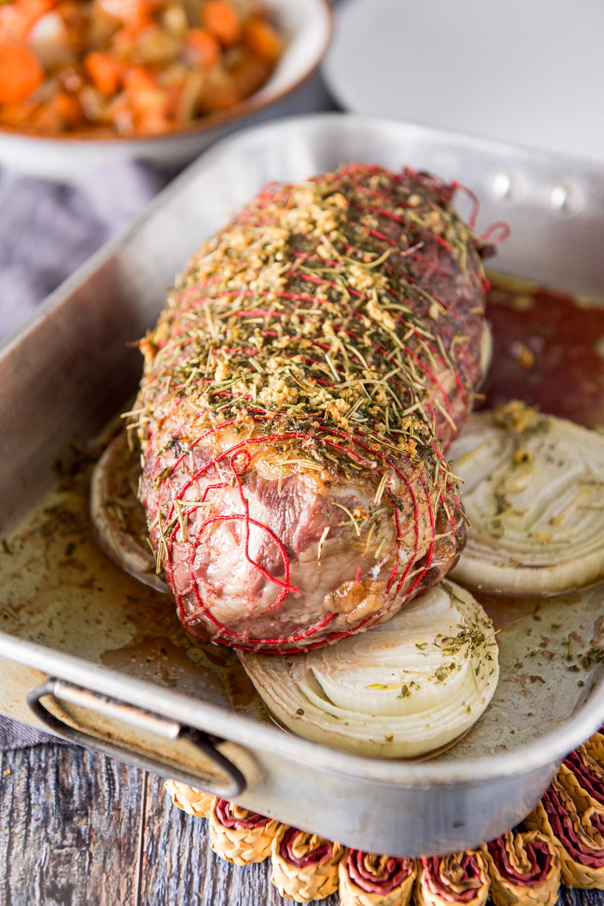 Lamb out of the oven with crispy garlic and lots of juice and some carrots in the background