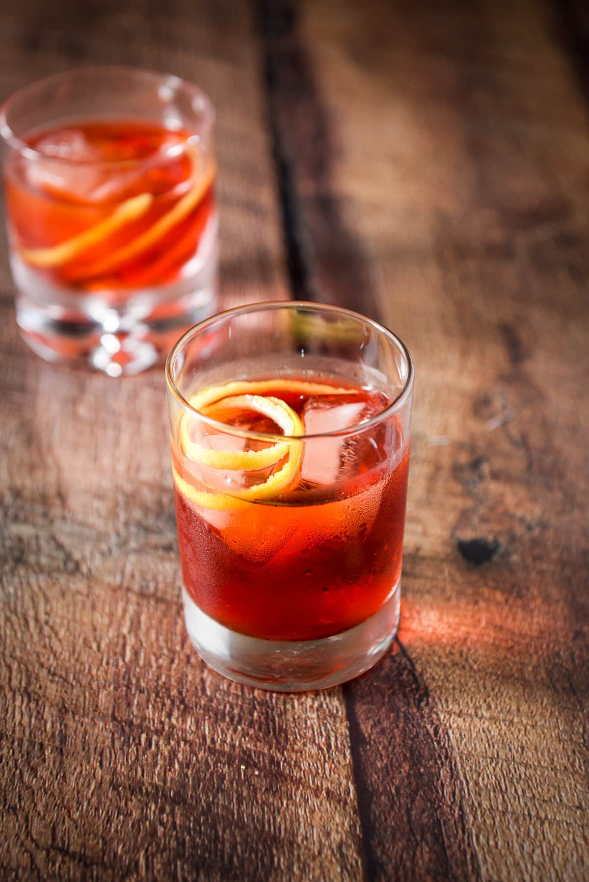 The taller double old fashioned glass filled with the negroni with the twist as garnish