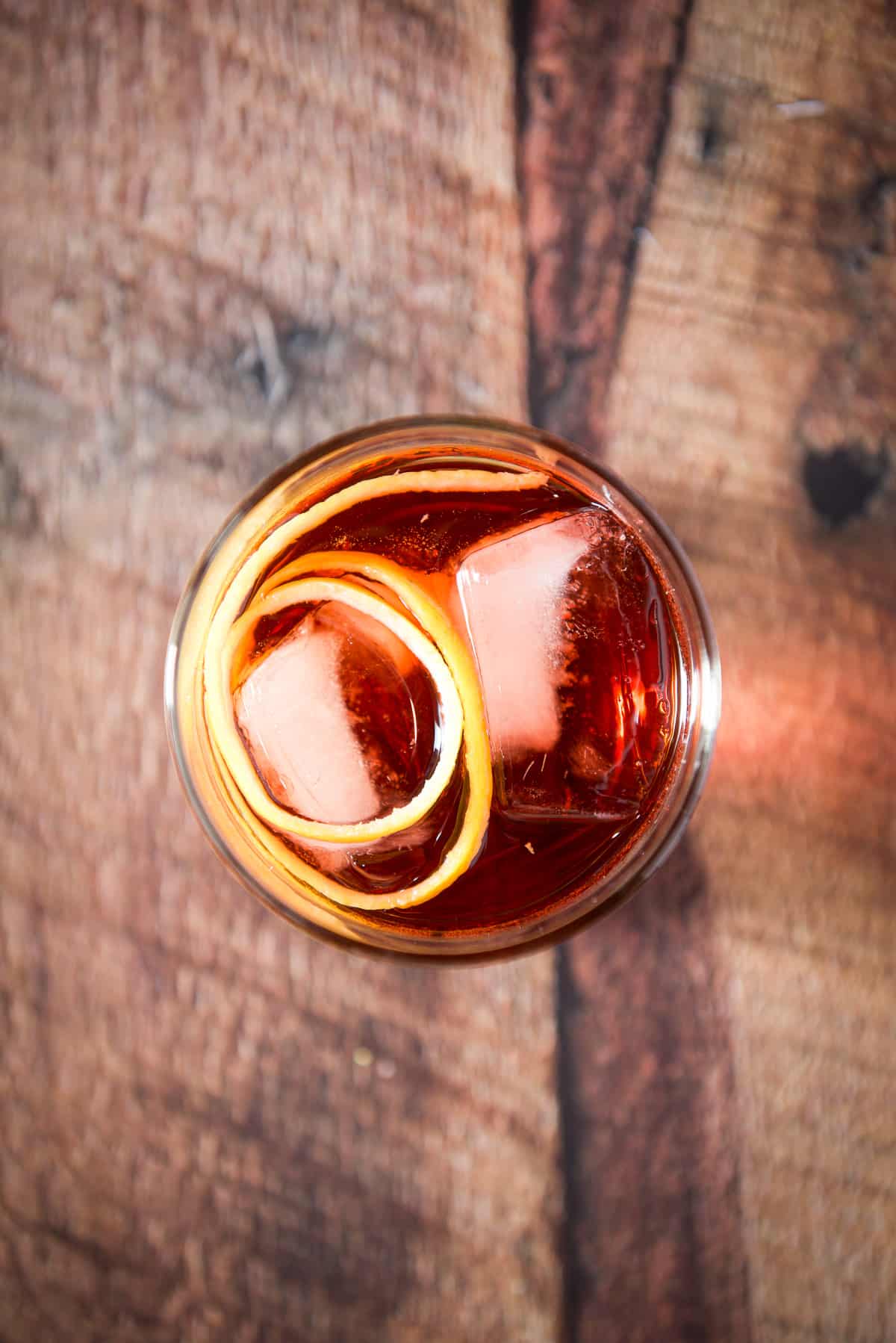 Overhead view of the red drink with the lemon twist on top of the ice cubes