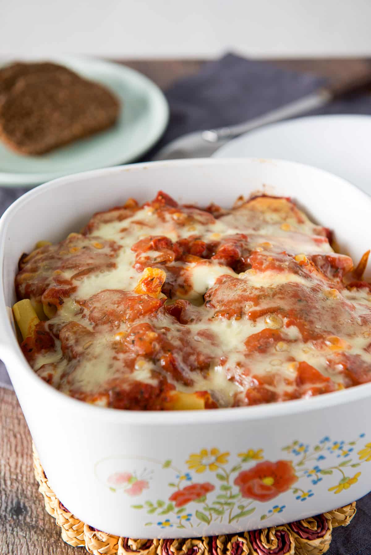 Casserole dish out of the oven with the cheese melted and bread in the background