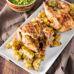 A white rectangle platter with two hens on it with potato wedges