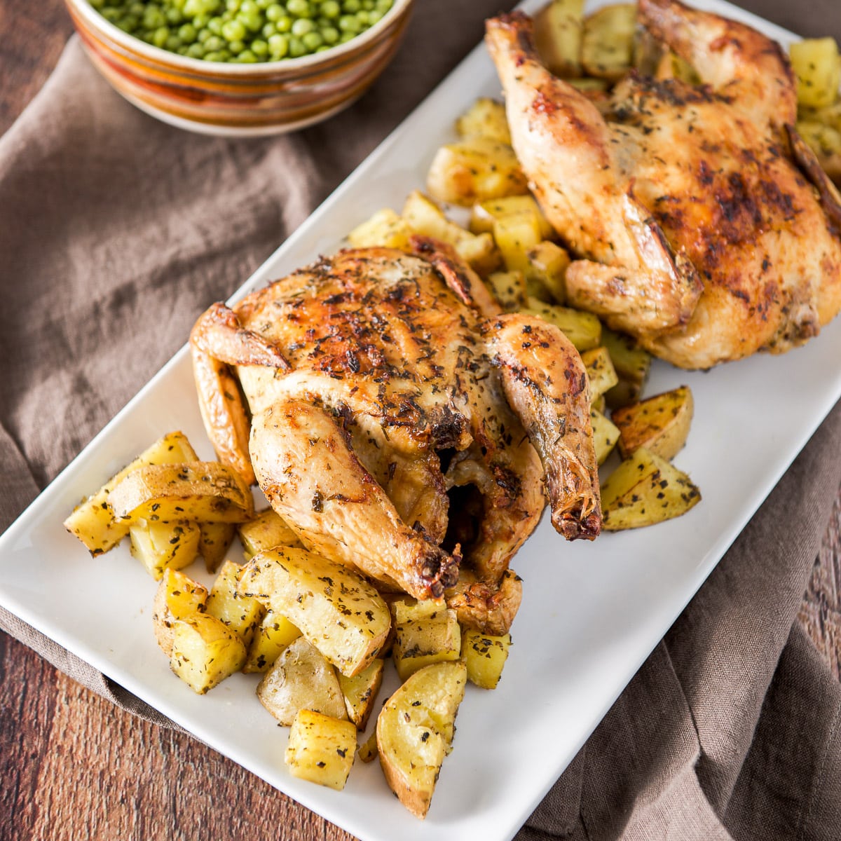 A white rectangle platter with two hens on it with potato wedges