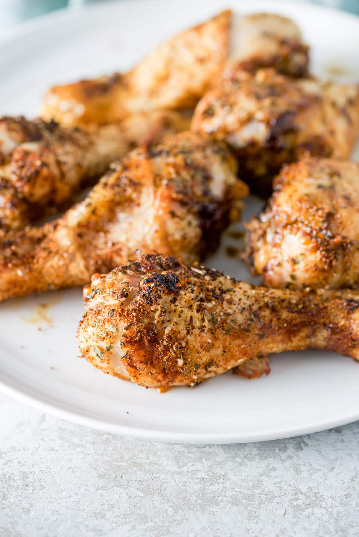 A white plate with cooked chicken drumsticks on it