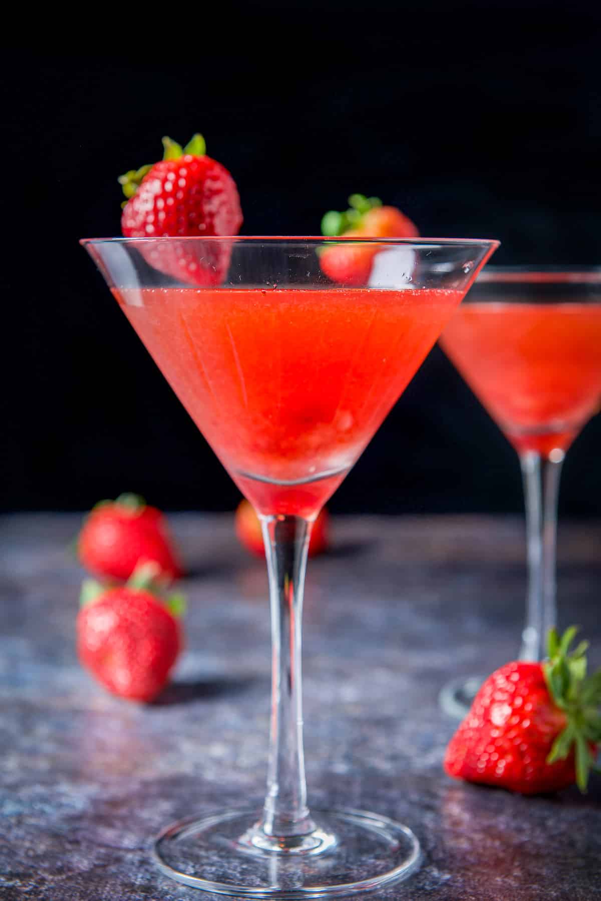 Vertical view of the strawberry cosmos with strawberries on the rims as garnish and table