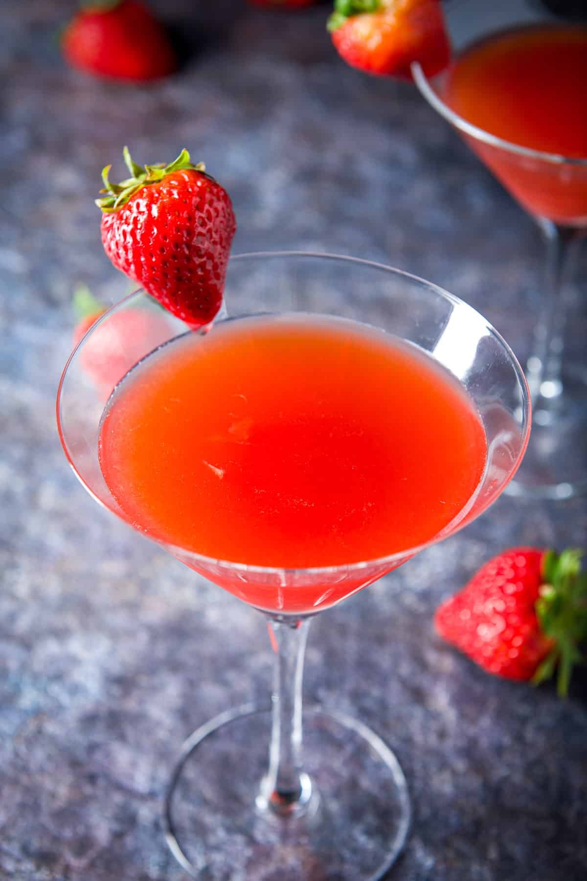Close up of the strawberry martini with strawberries on the table and rims