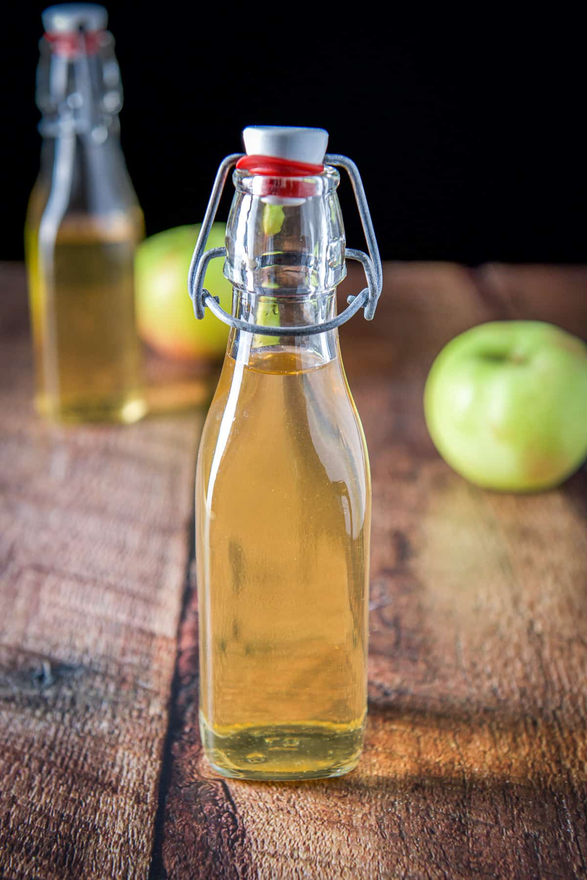 Two bottles of flavored vodka with two apples on a table