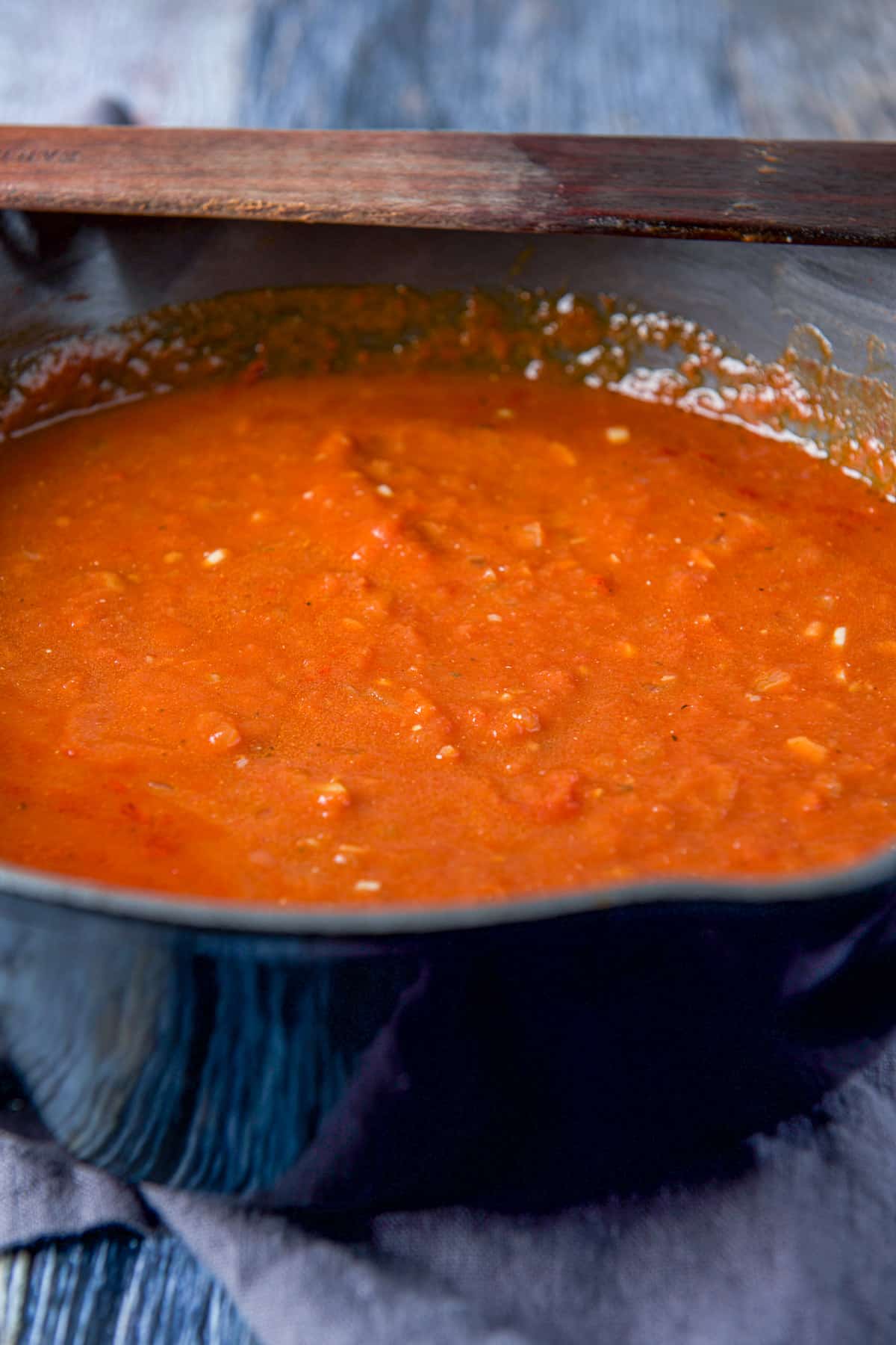 Pan of sauce with a wooden spatula on the rim