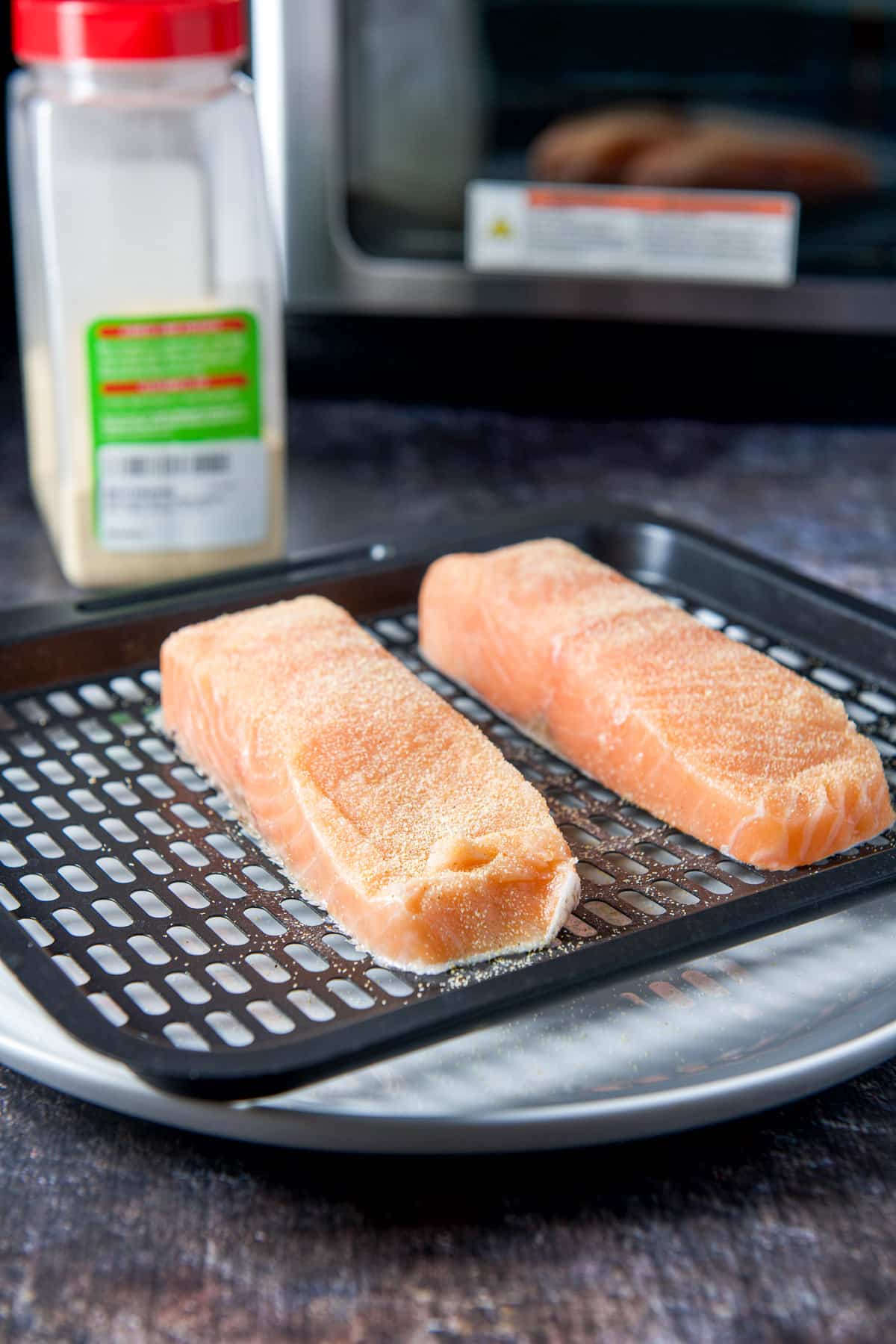 A tray with the salmon that has been salted and has garlic powder on it