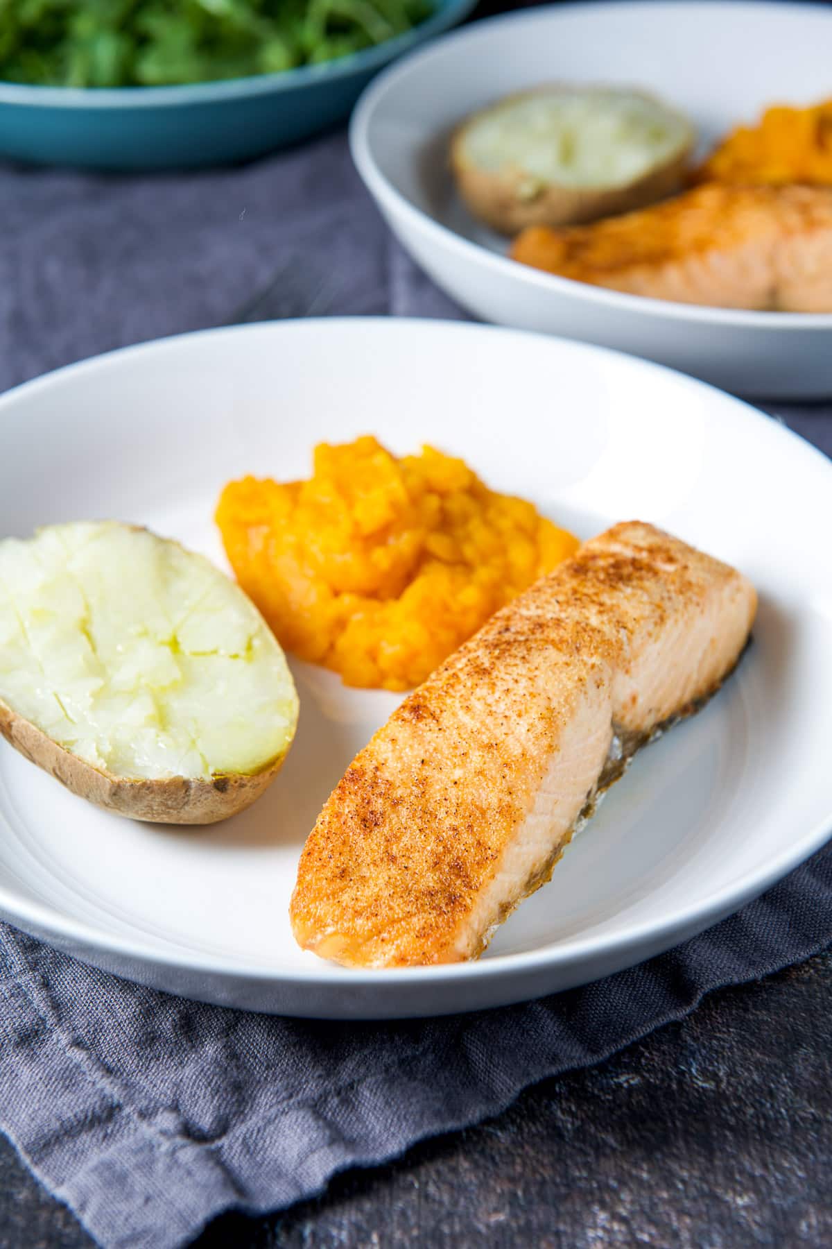A white deep dish with the salmon, squash and potato