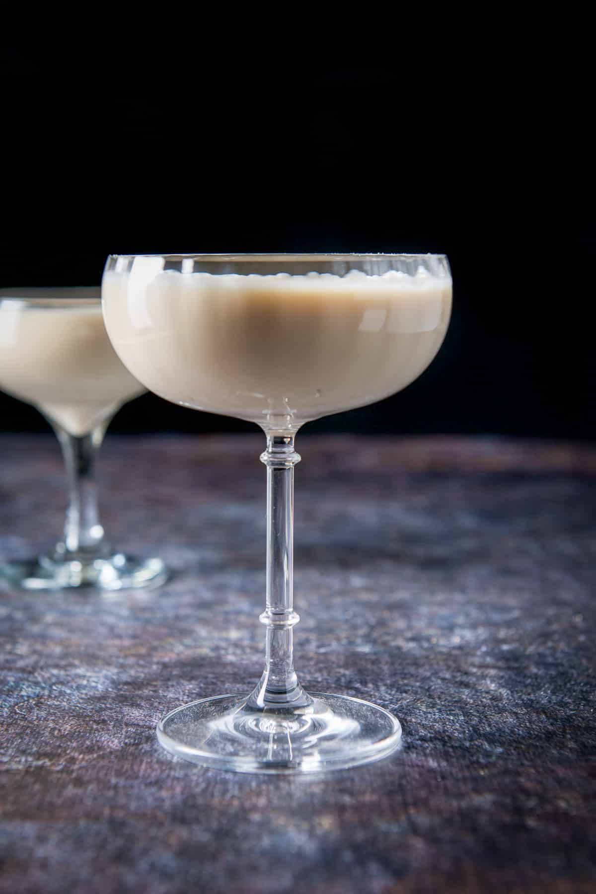 Tall fluted coupe glasses filled with the creamy drink in vertical view