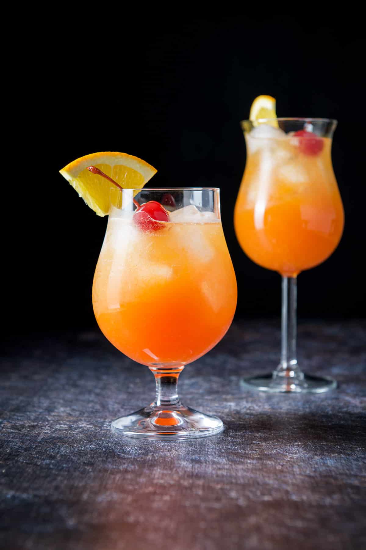 The shorter glass in front in vertical view filled with the hurricane drink