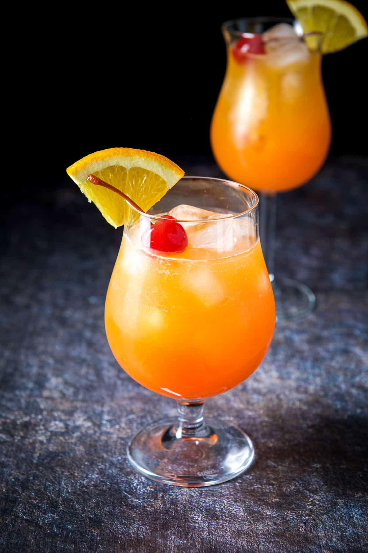 Two tulips filled with the hurricane cocktail with garnish on the rim