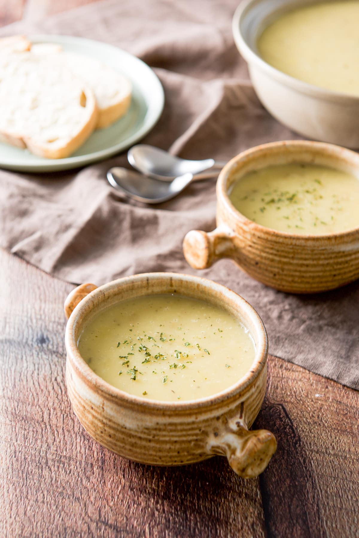 Two crocks filled with potato soup with sprinkles of parsley