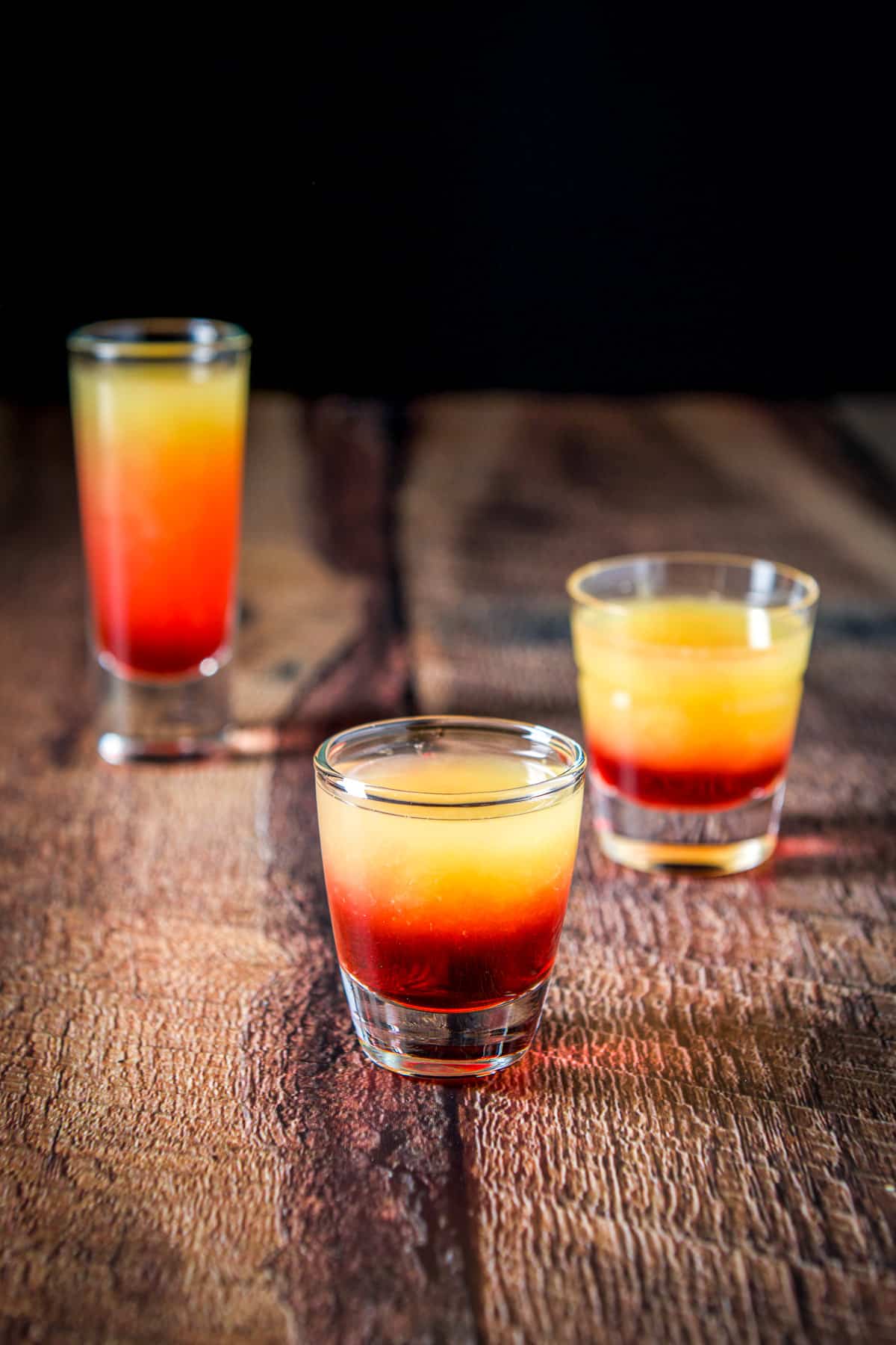 A smooth small glass in front of the other two filled with the layered shot