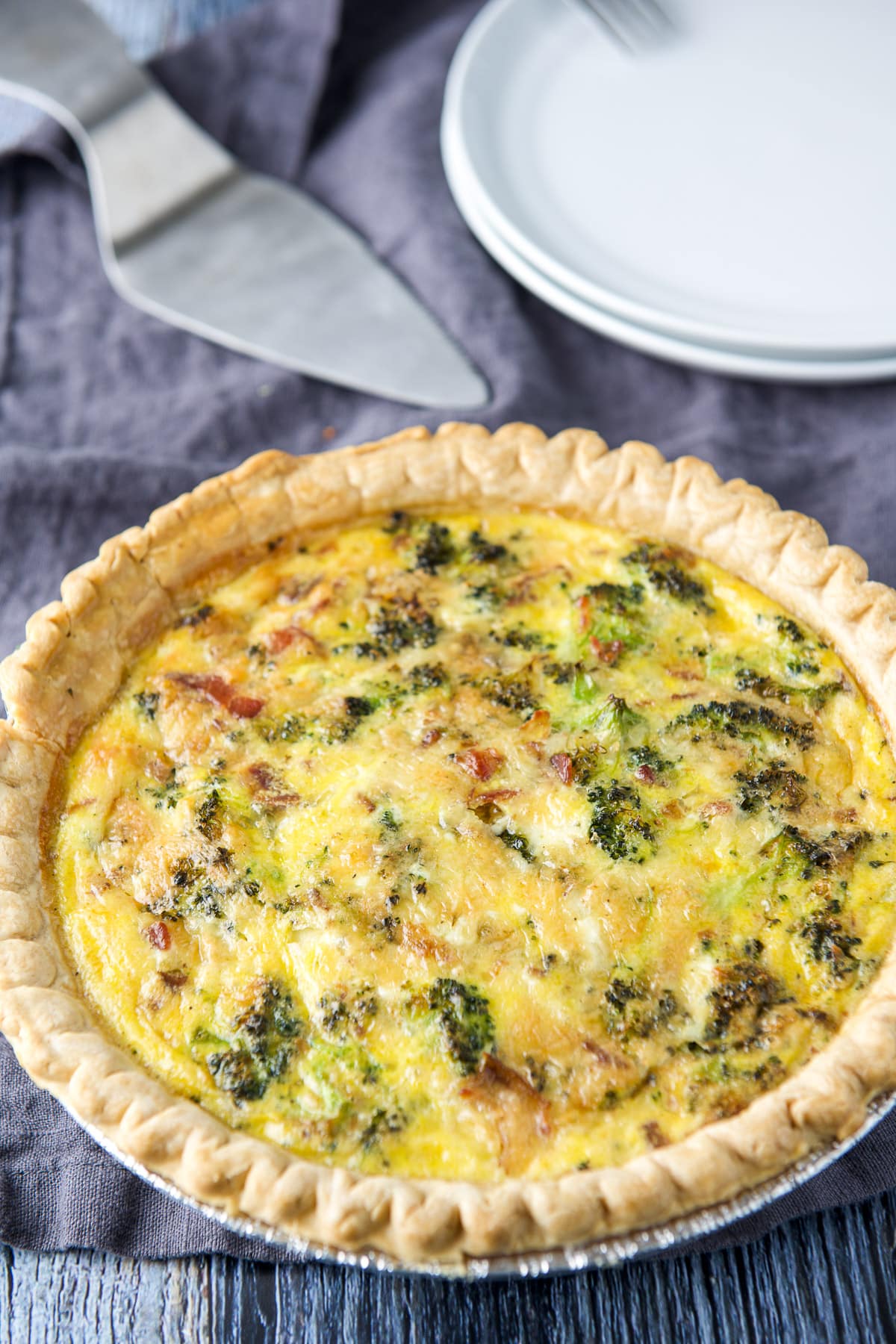 Quiche fresh out of the oven with white plates and a server