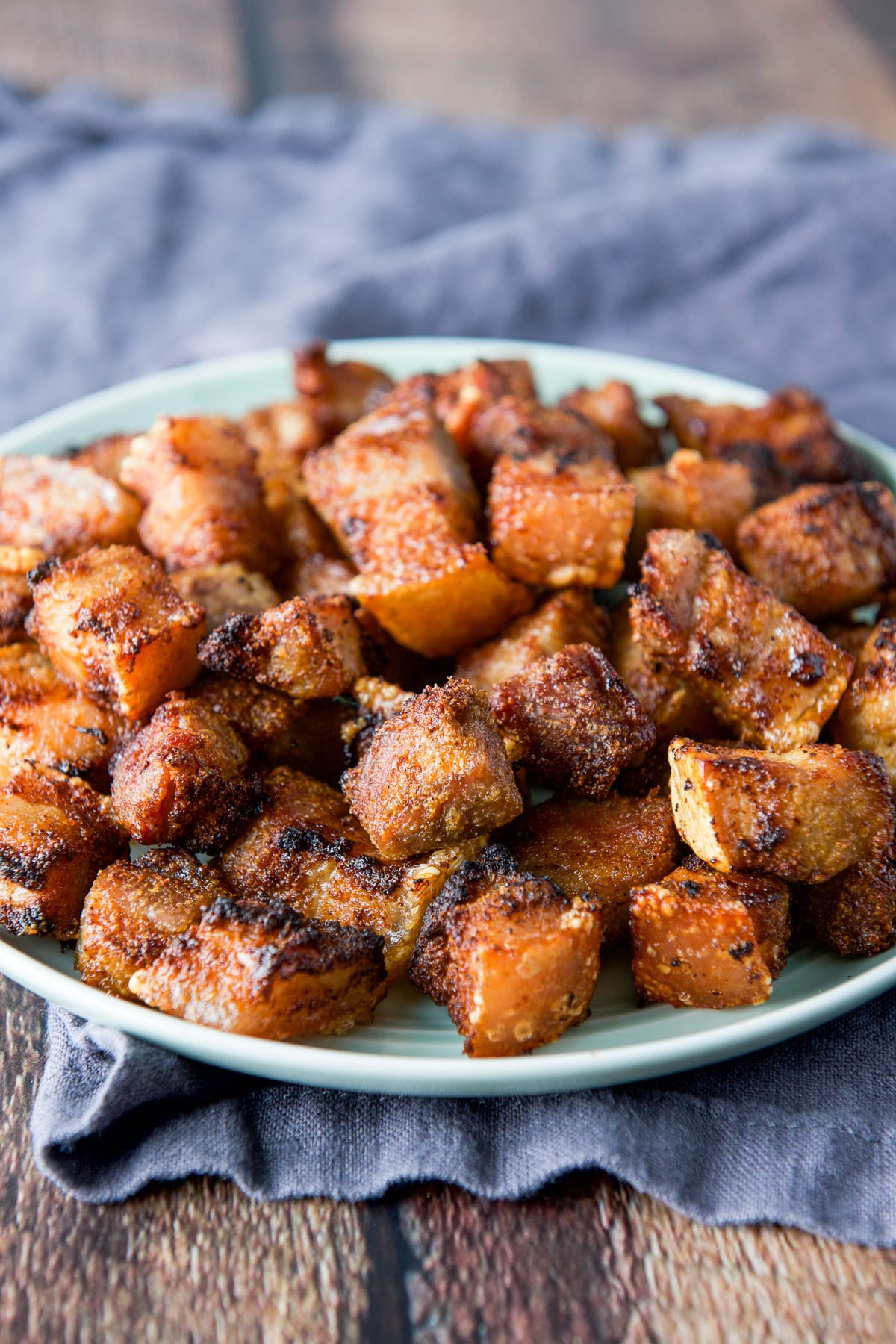 A green small plate with crispy pork belly bits on it
