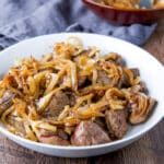 A white bowl with chicken livers with onions on top - square
