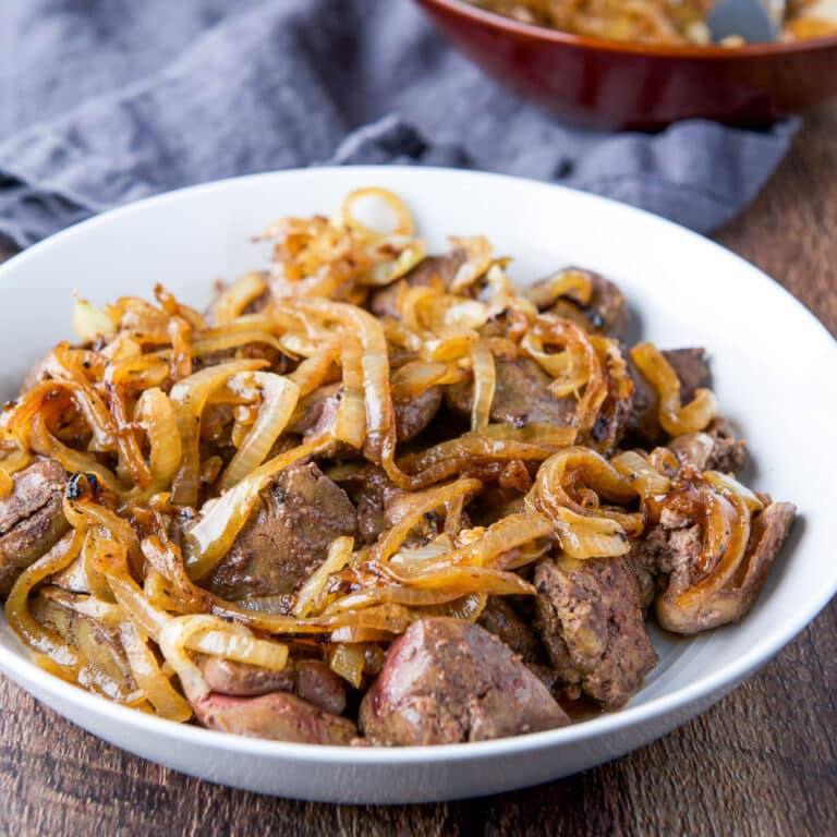 A white bowl with chicken livers with onions on top - square