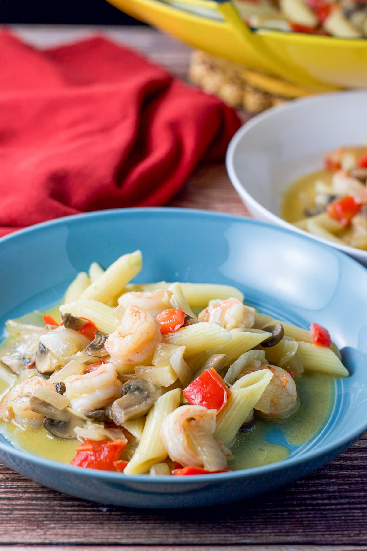 A blue bowl with shrimp and pasta in it