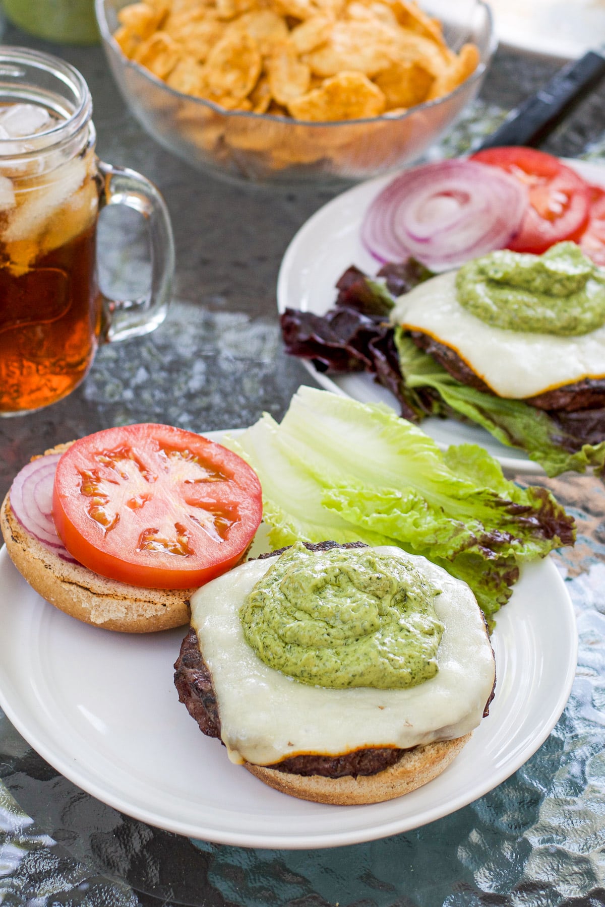 Avocado sauce on a burger with chips and tea in the back