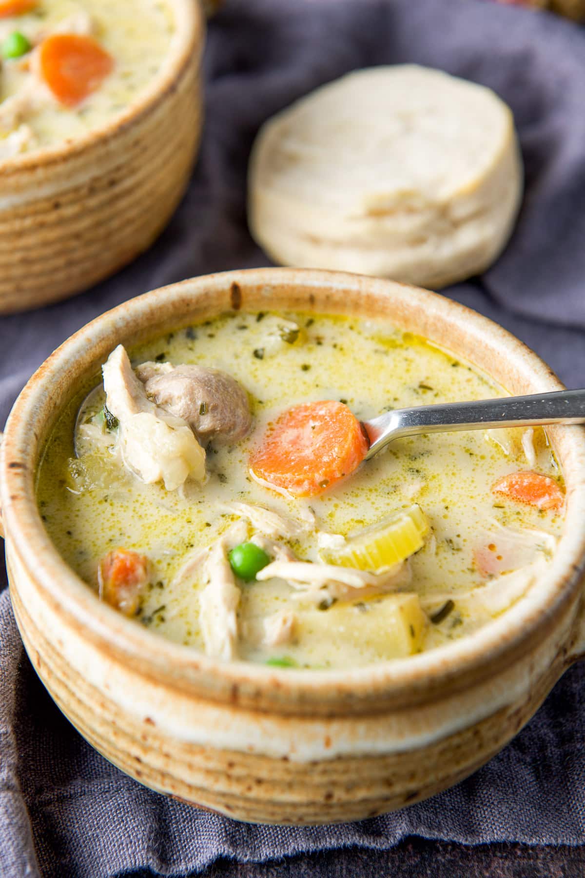 Close up of the creamy chicken soup with a biscuit in the back