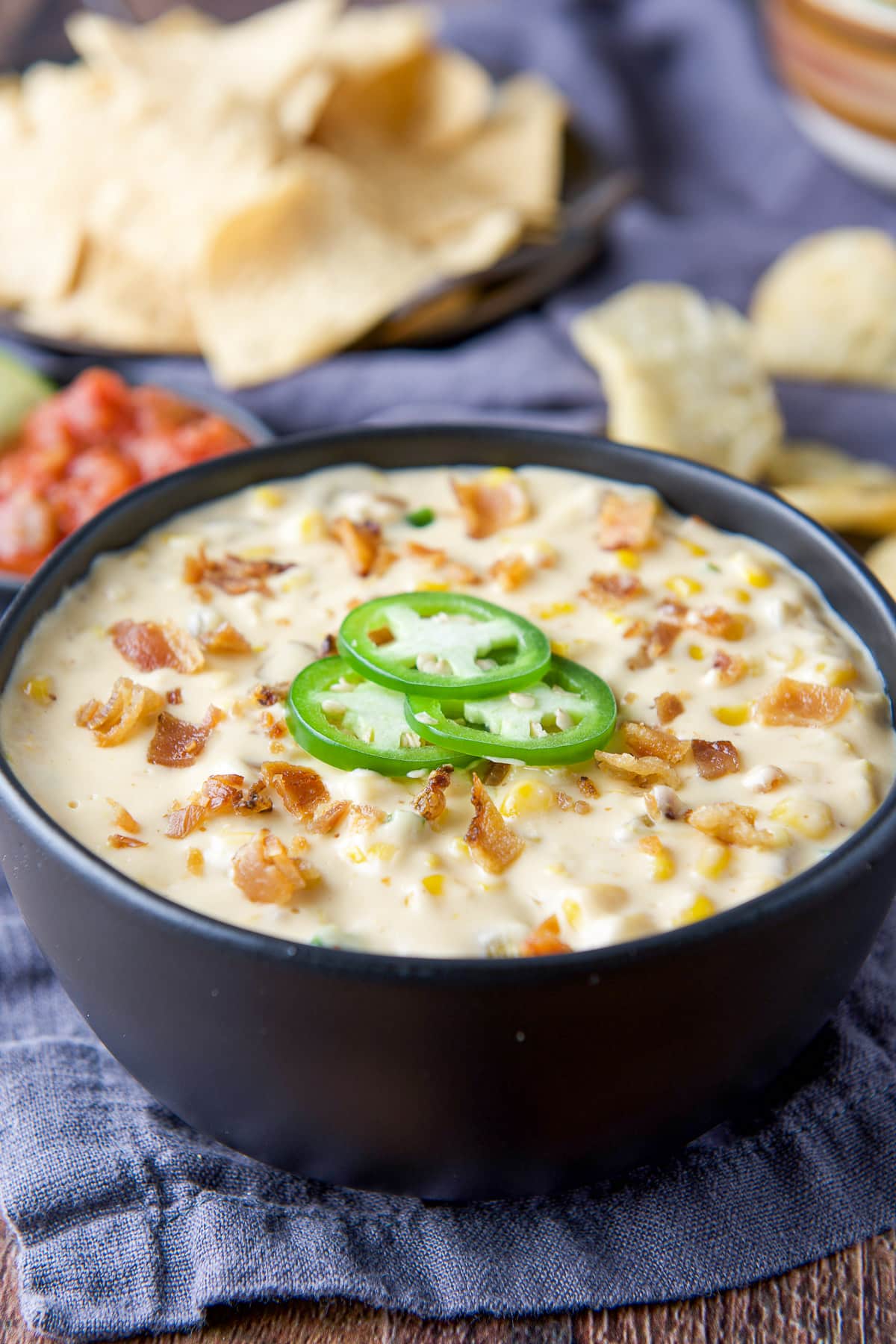 Close up of a black bowl filled with the dip with bacon crumbled on top and jalapeno slices on top