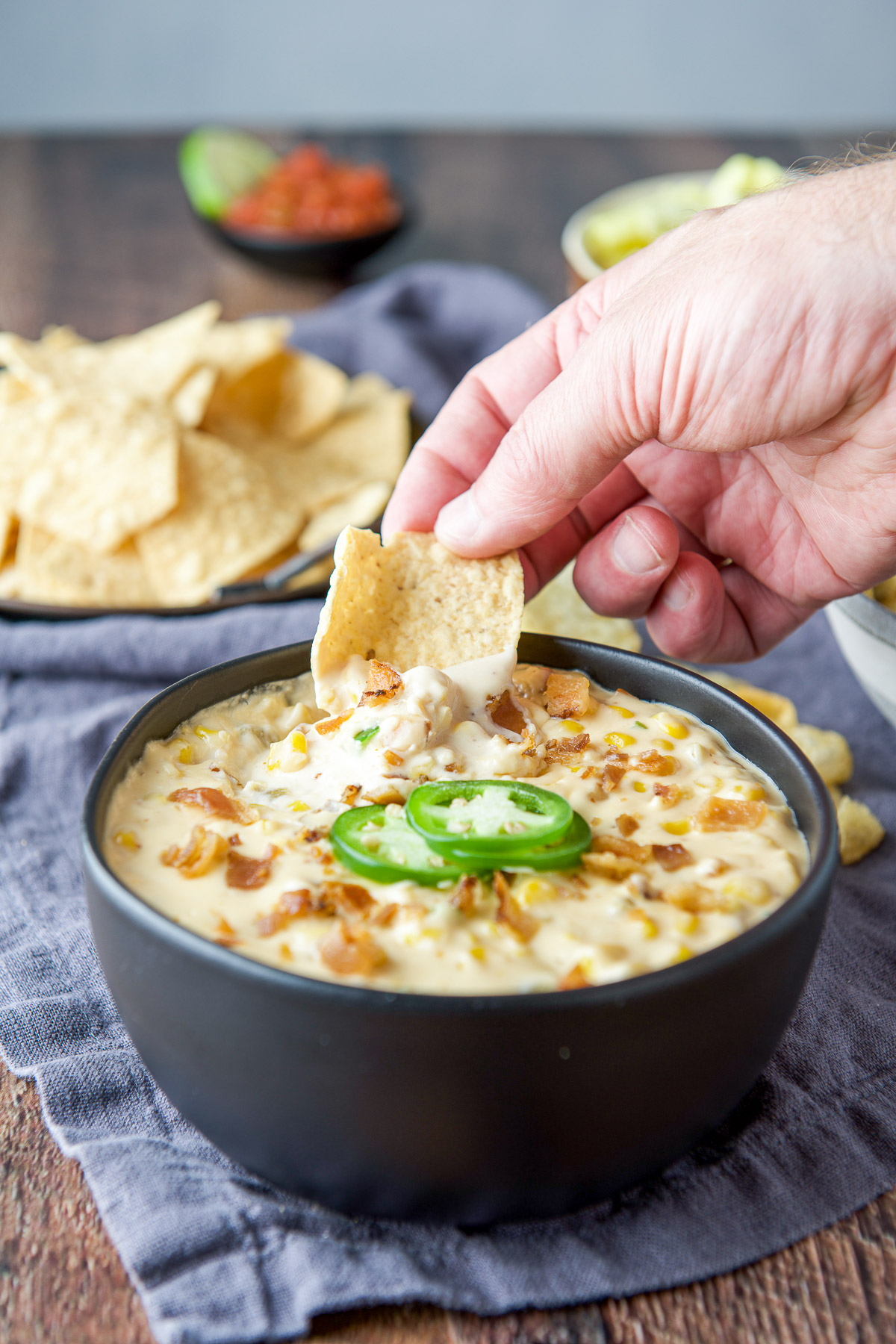 A male hand holding a chip in the bowl of dip