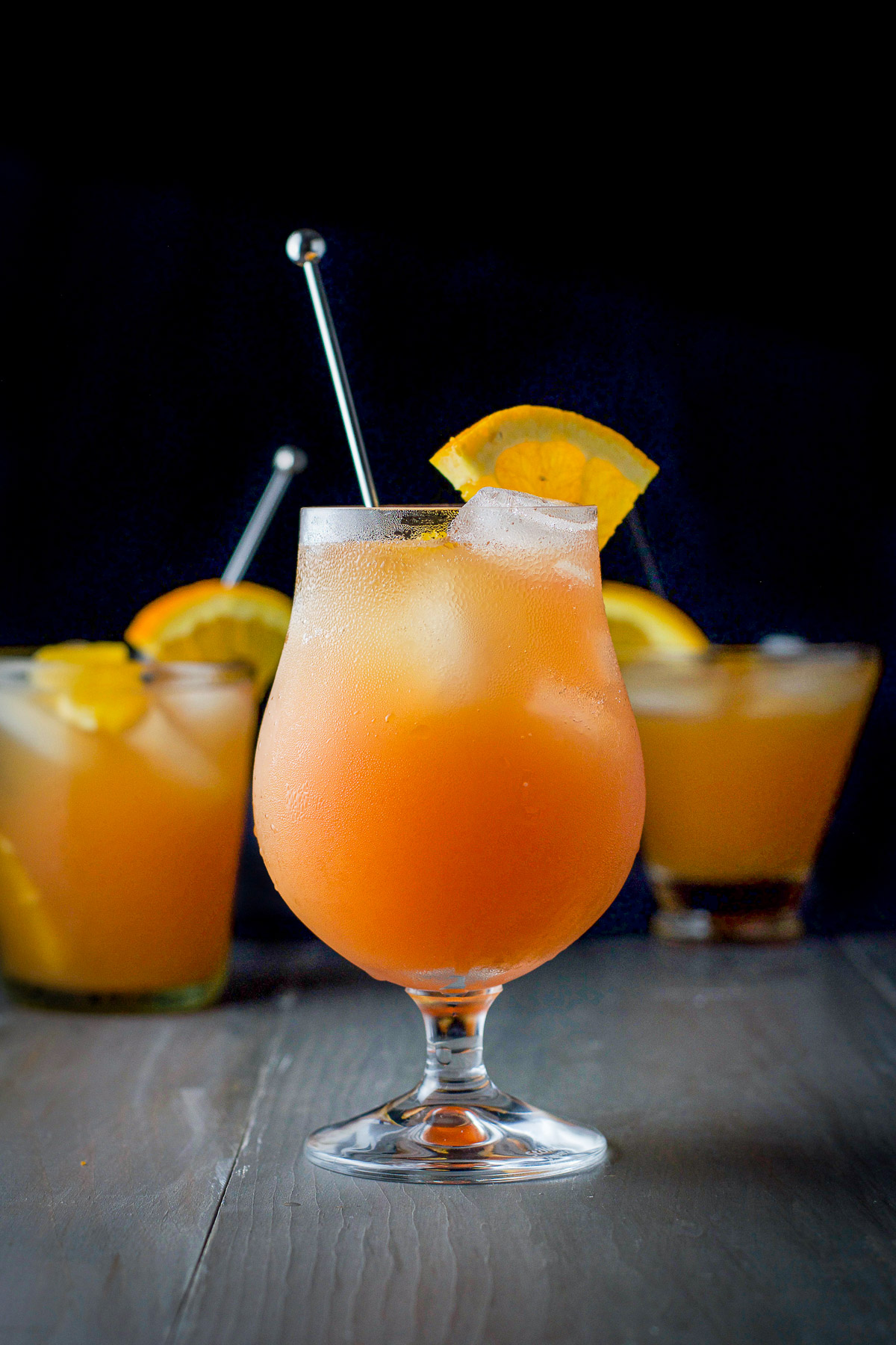 vertical view of the tulip glass filled with the rum drink with two glasses in the back
