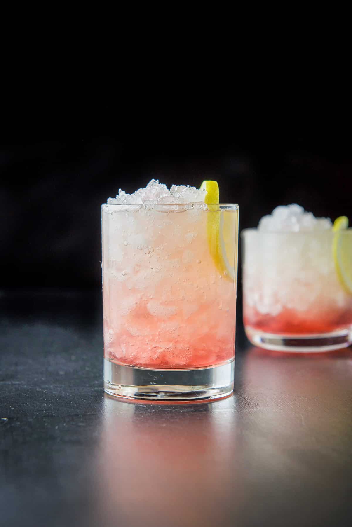 Taller glass filled with ice, bramble and lemon slices