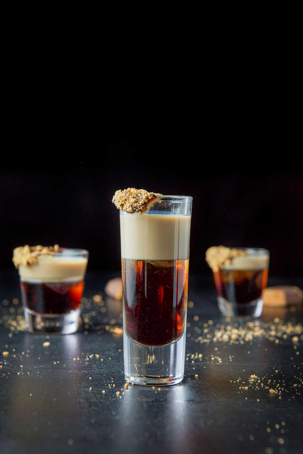 vertical view of the tall glass with the layered shot and a candy bar covered rim