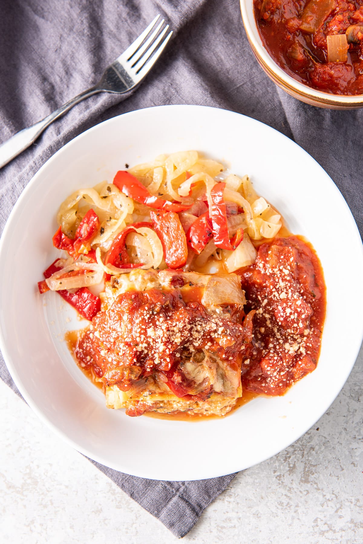 Overhead view of a white plate with lasagna, sausage and vegetable