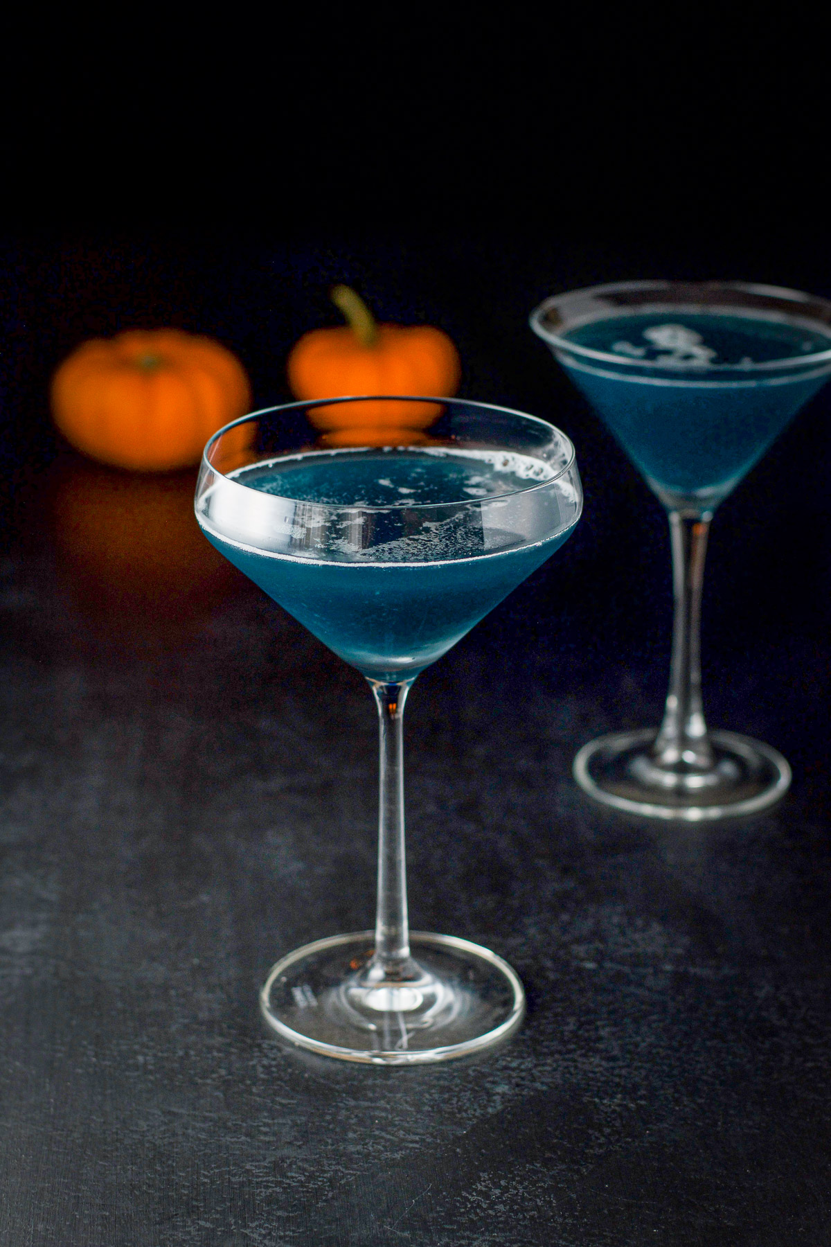 two martini glasses filled with the blue cocktail