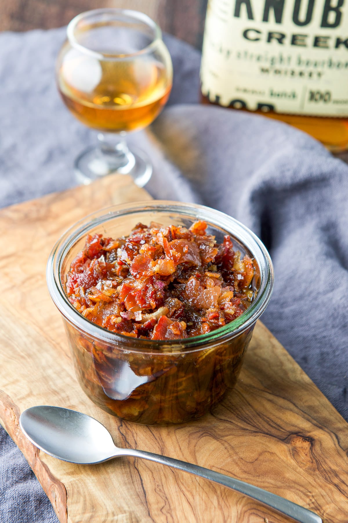A jar filled with the jam with bourbon in the back