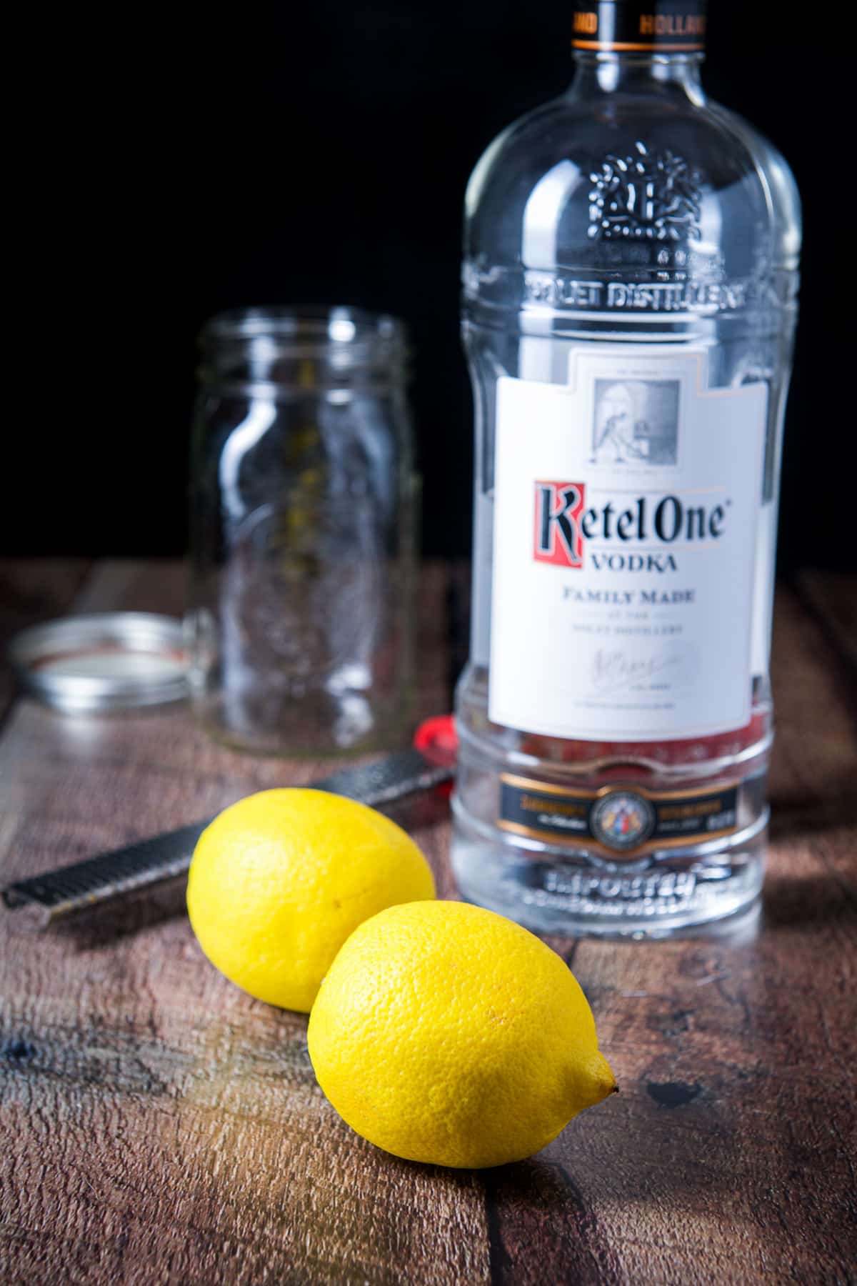 Lemons, vodka, microplane, and jar on the table