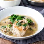 a pork chop with vegetables and broth in a deep dish - square