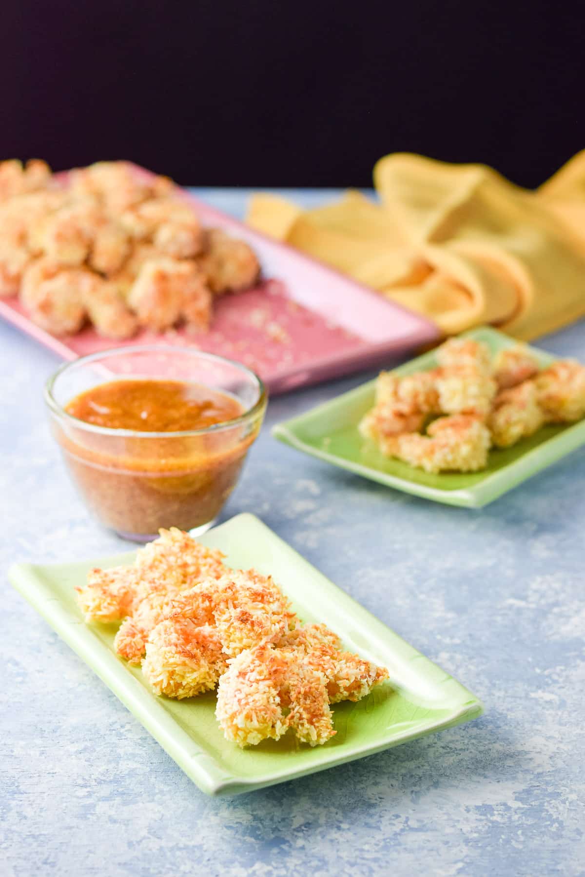 Two green plates with the shrimp appetizer on them with sauce close by