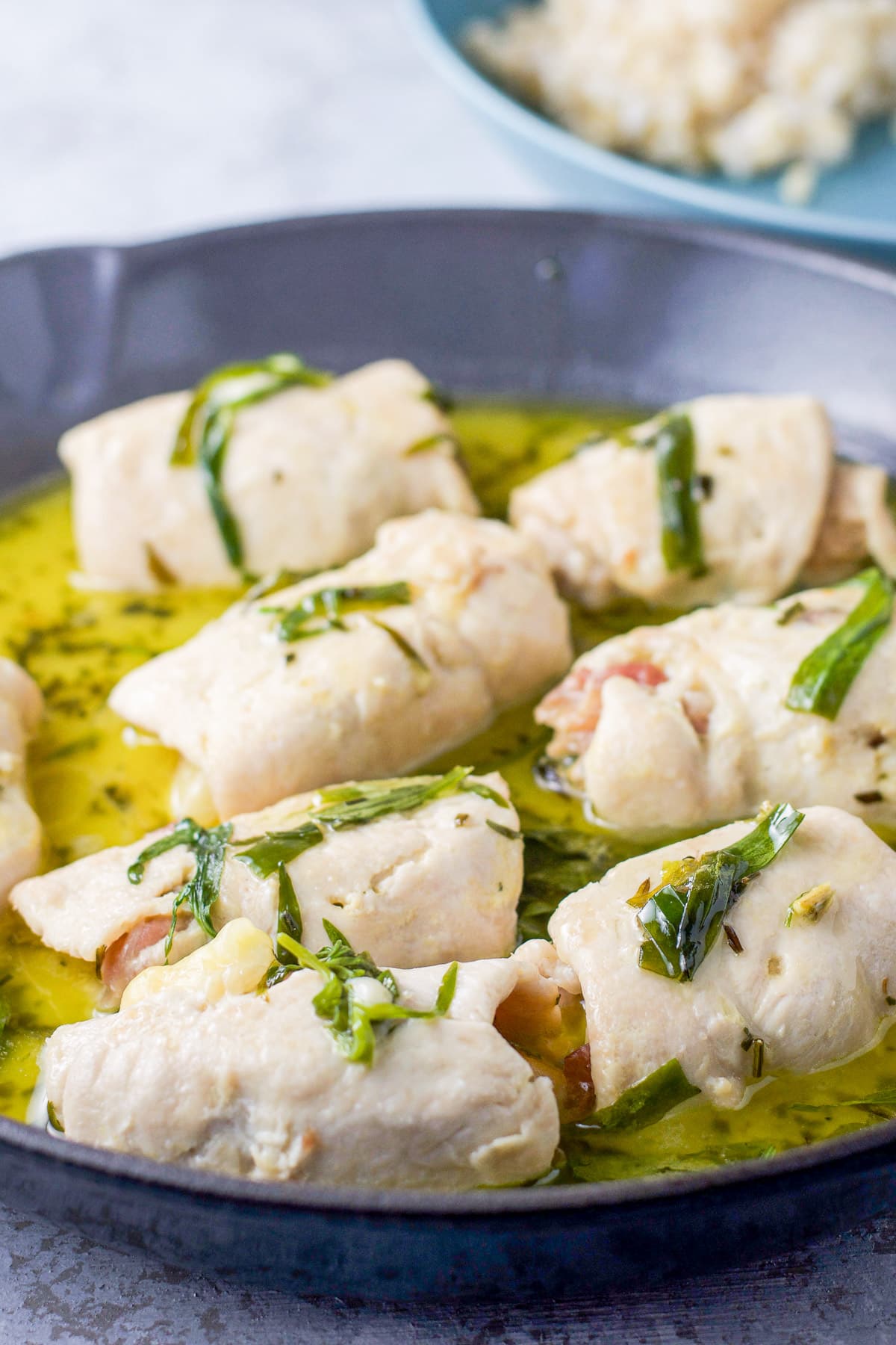 A pan with the chicken rolls in a butter sauce