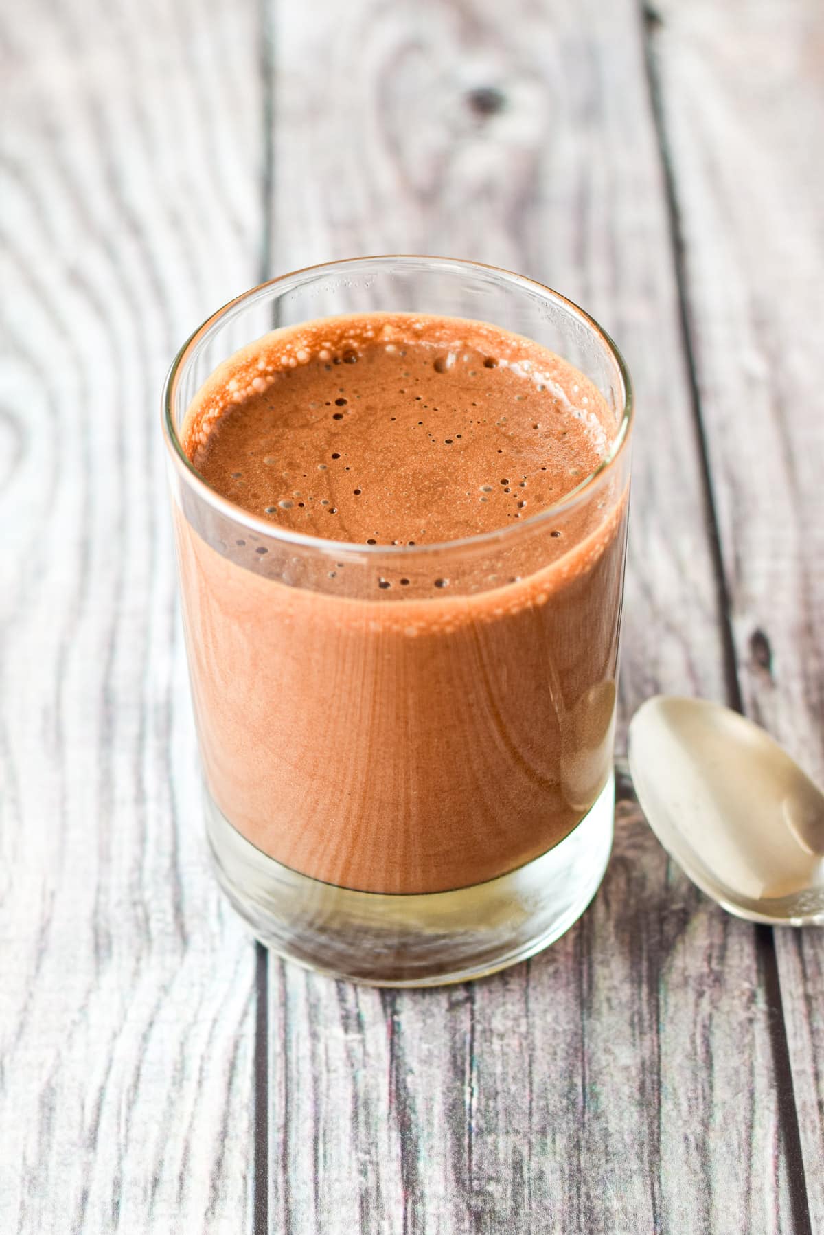 A glass filled with the mousse in it on a grey table