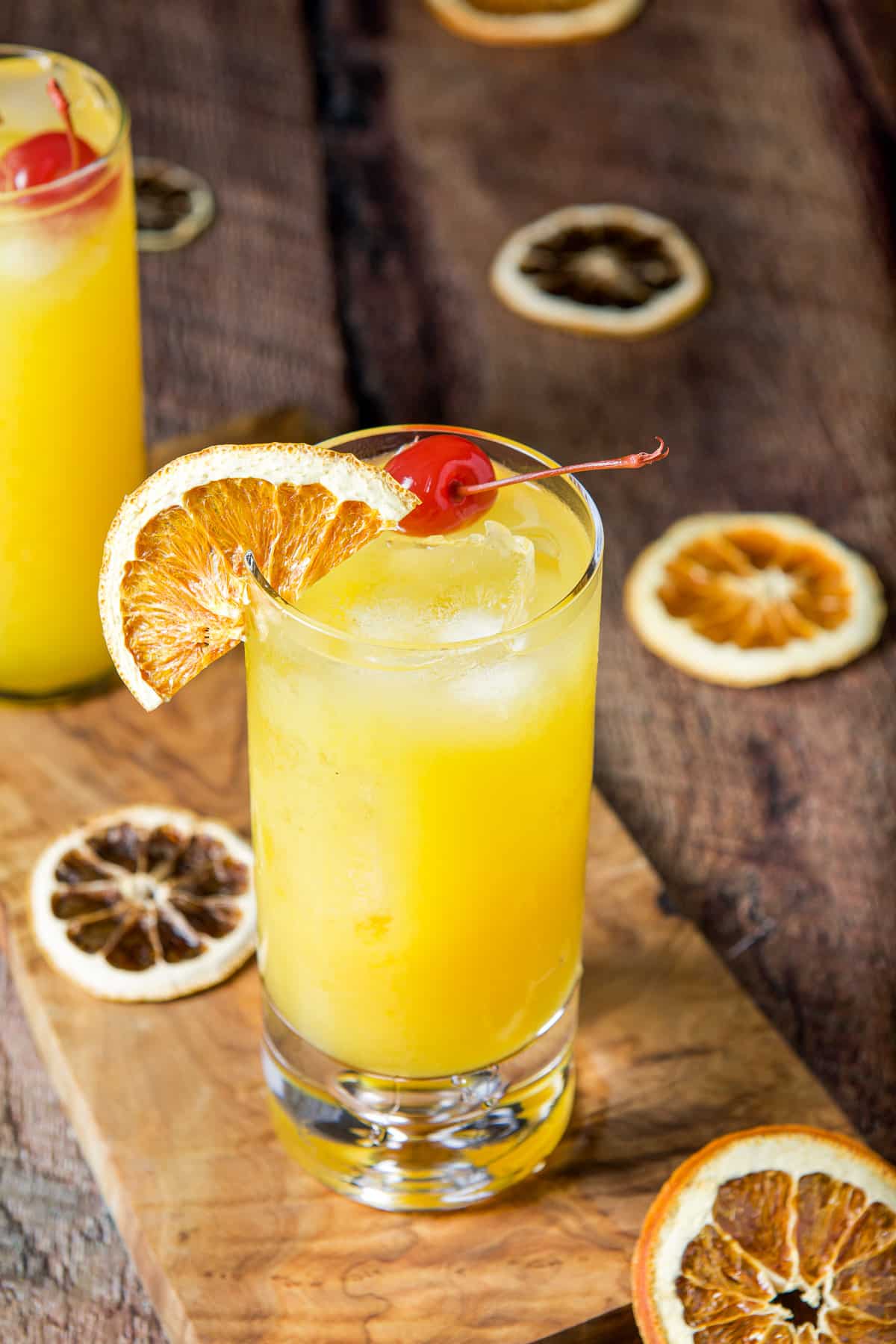 High view of the tall glass on a board with the garnish on the table and in the drinks