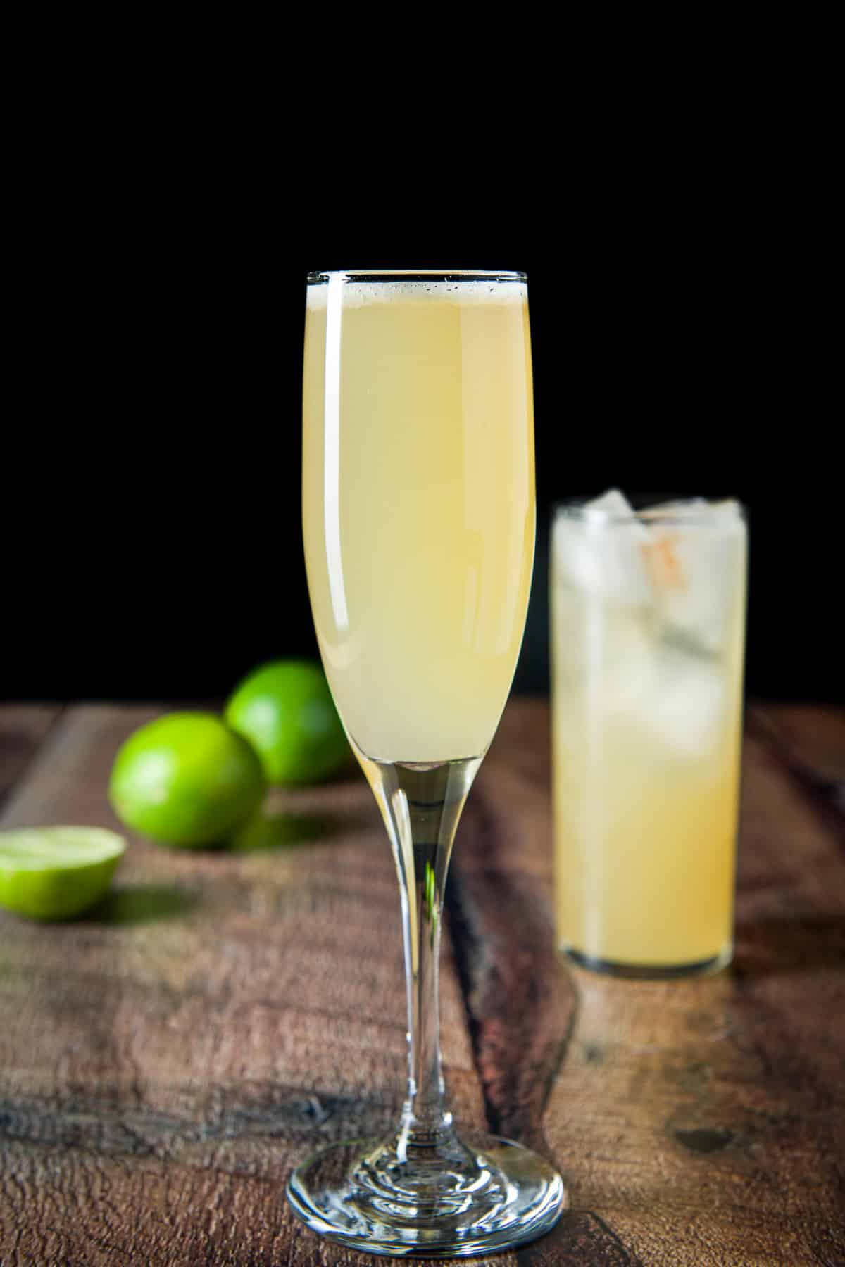 Vertical view of the champagne flute in front of the tall glass with ice and the cocktail