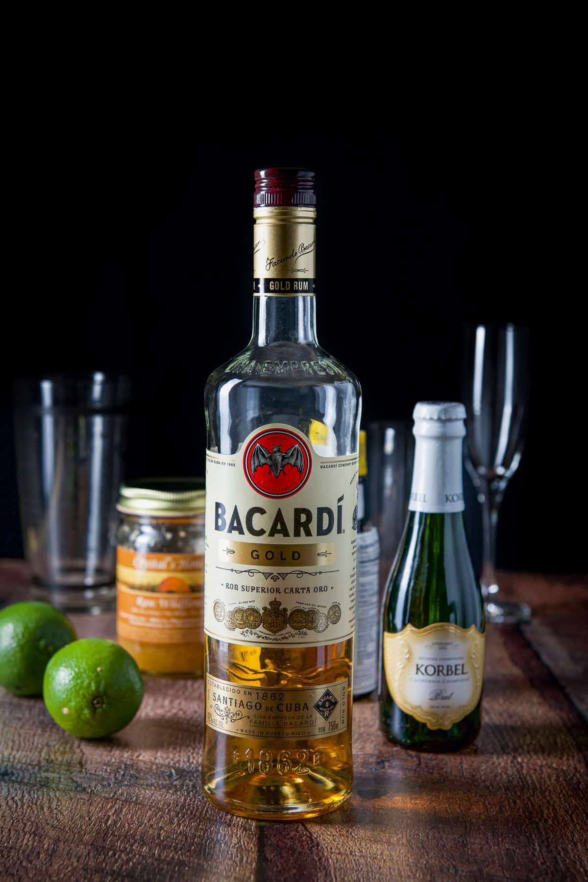 Rum, limes, champagne, honey and glasses on a table