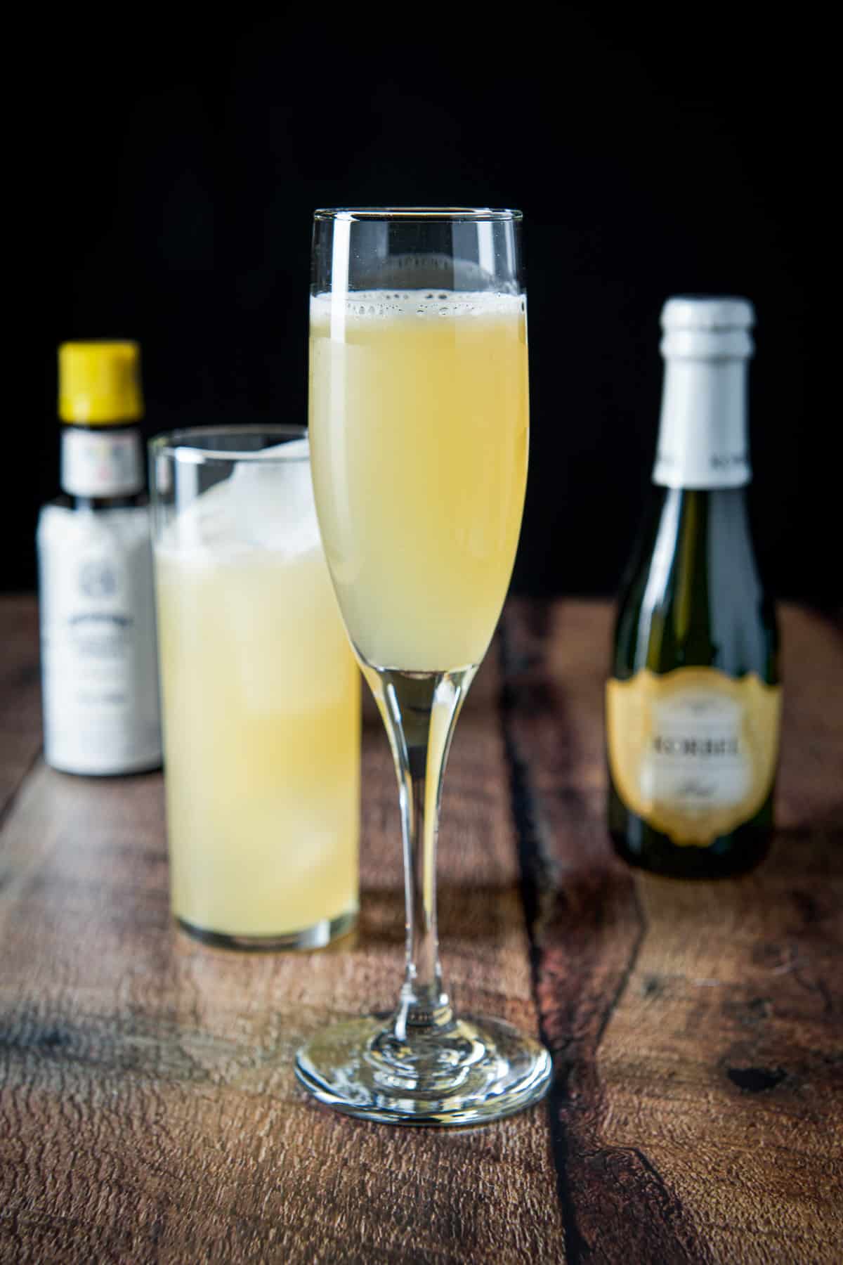 The cocktail shaker emptied into the glasses with champagne and bitters in the back