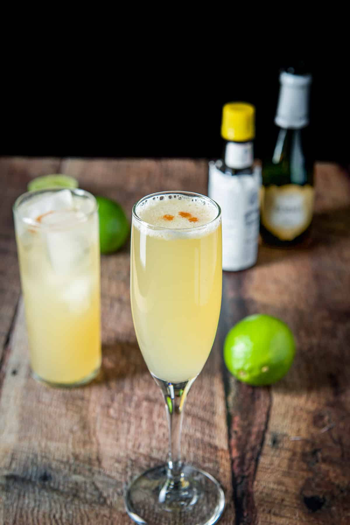 Three drops of bitters added to both cocktails with the champagne and bitter bottles in the back