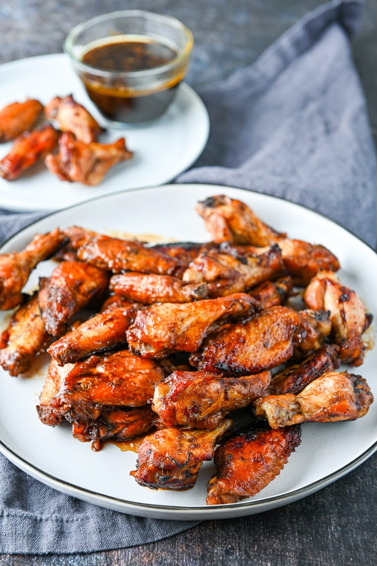 A platter with chicken wings with a small plate with some sauce and wings