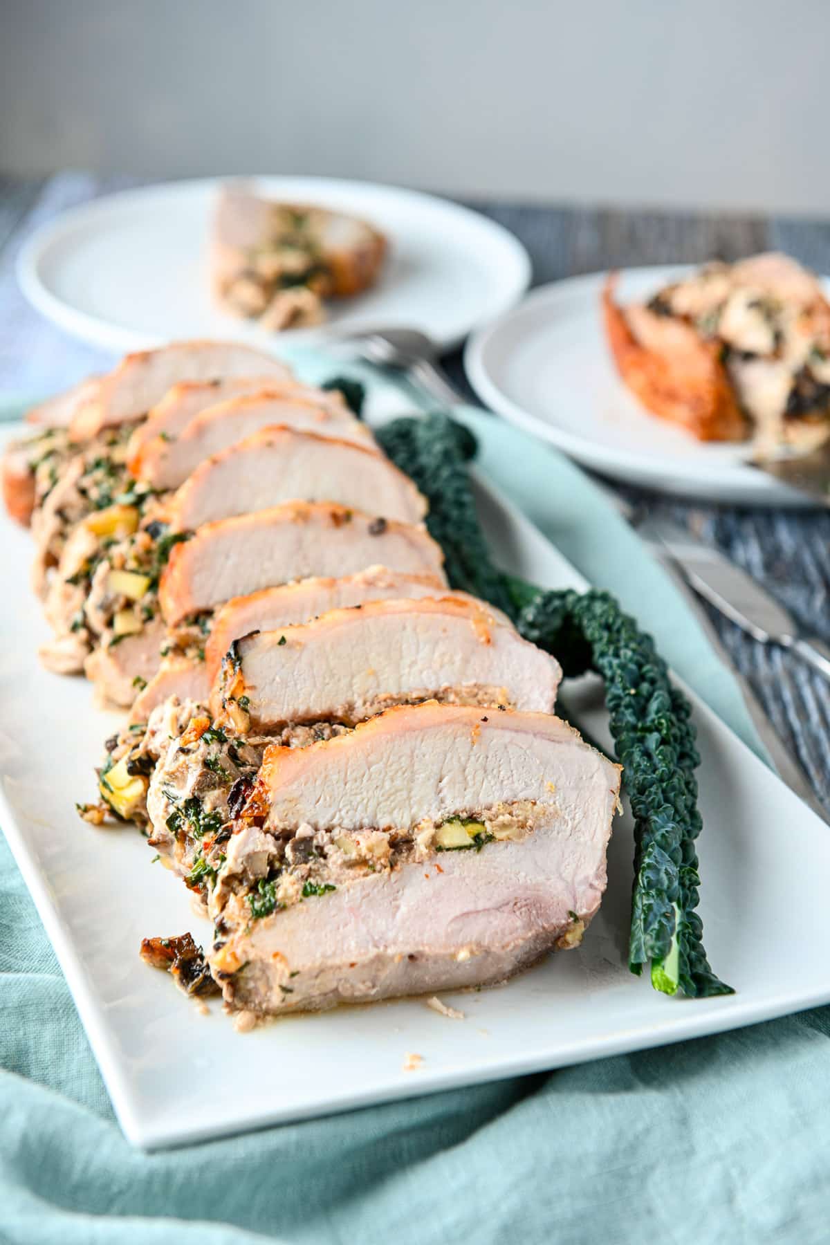 Pork sliced and laid on a platter with the stuffing leaking out to the left