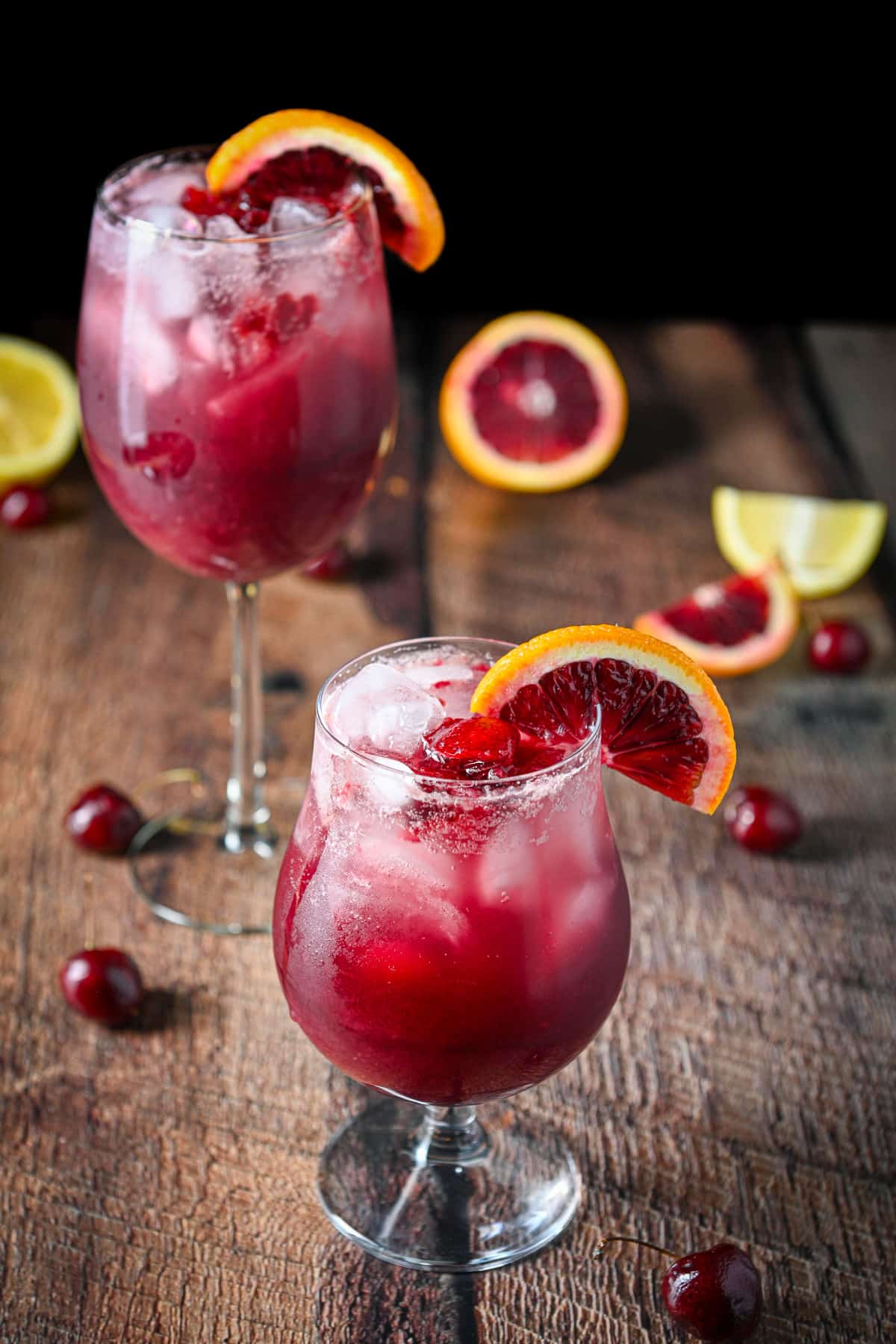 Fruit on the table with orange slices on the rim of two glasses with sangria in them
