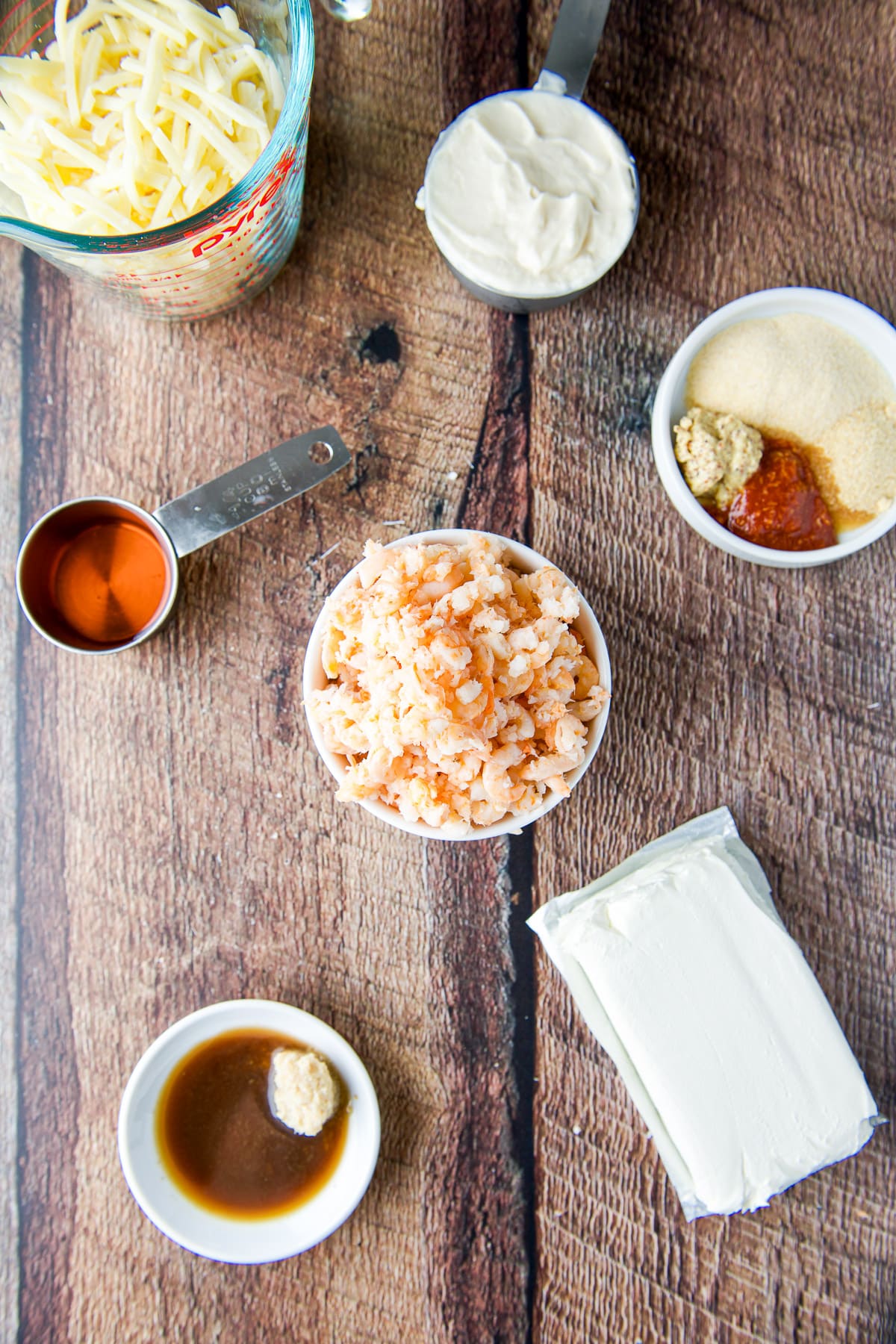 Overhead view of the ingredients - canned shrimp, spices, mayo, cheeses, rose wine, and sauces
