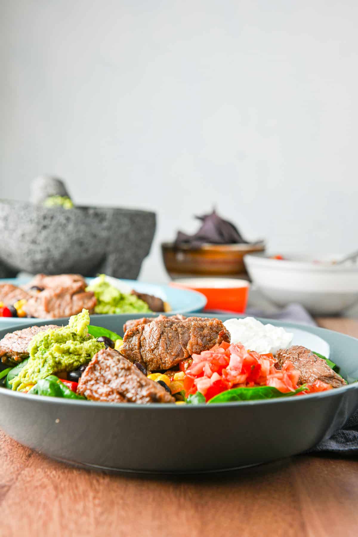Vertical view of two burrito bowls with guac and chips in the back