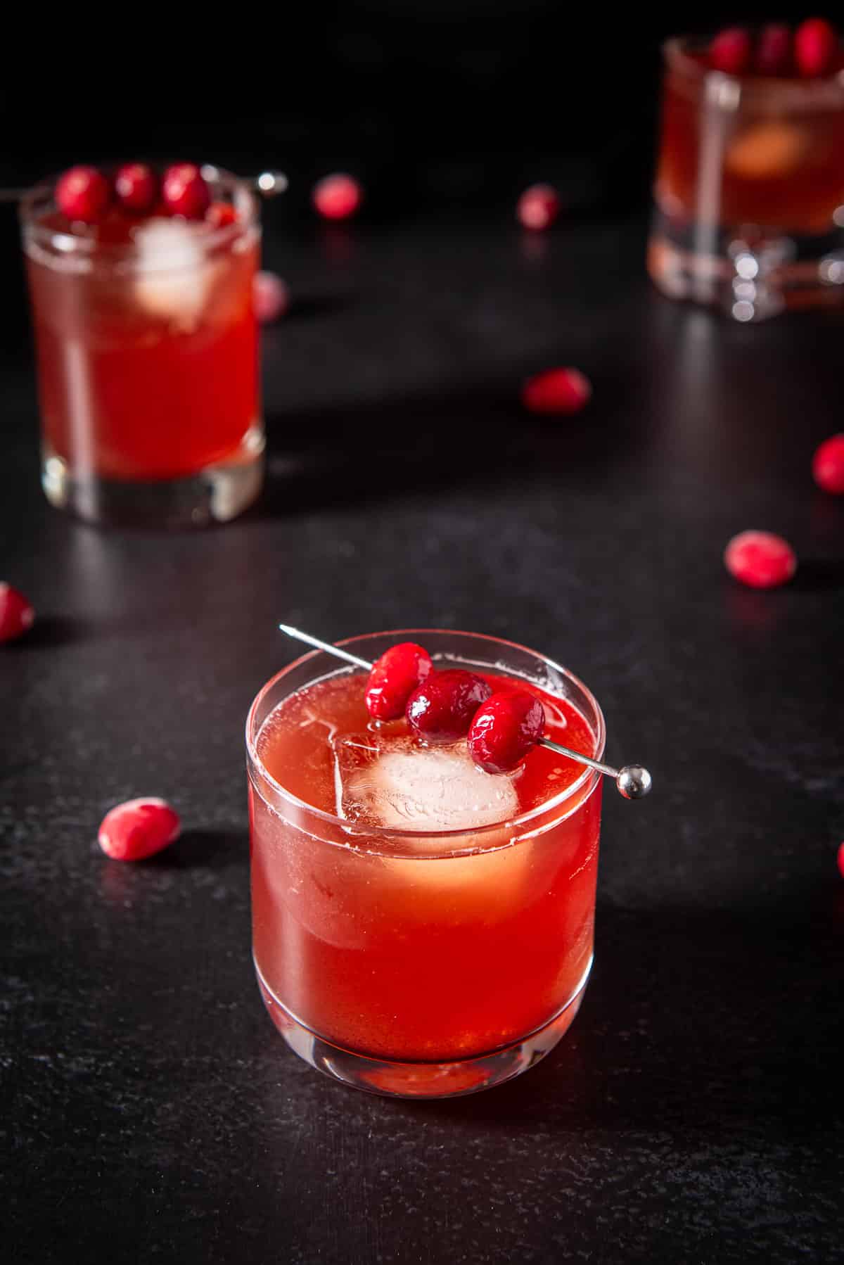 Closer view of the cranberry cocktail with cranberries on skewers and on the table with the other drinks